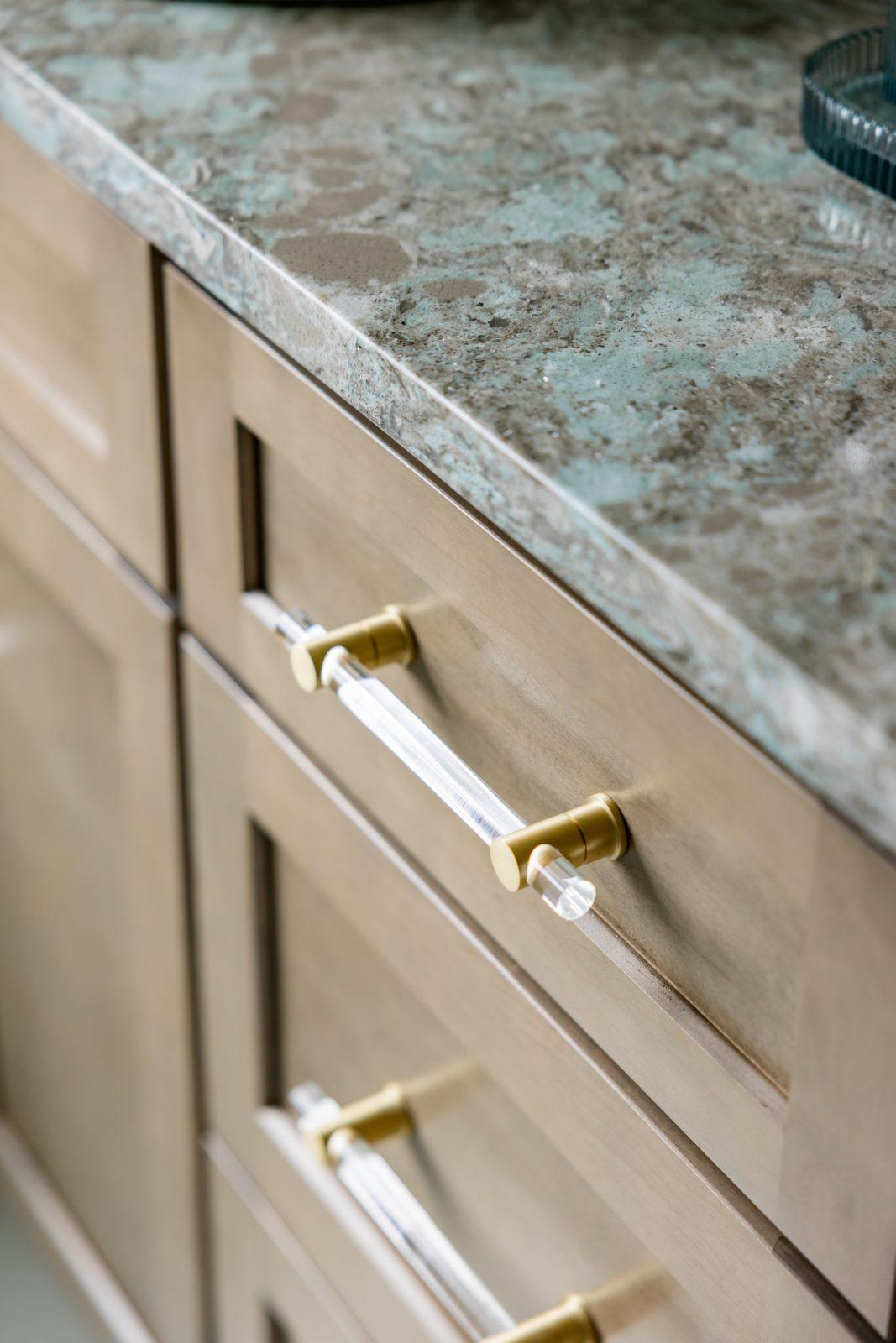 Cream vanity with brass hardware and green marble countertop detail by Design House Interiors