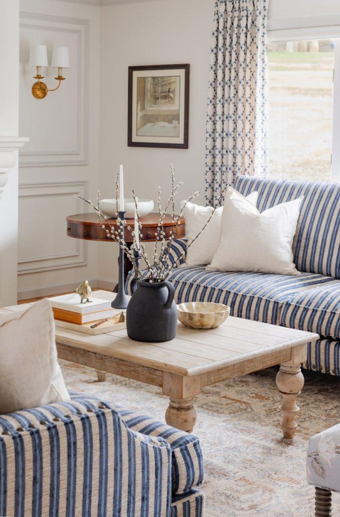 Living room with striped sofa, wooden coffee table, and patterned curtains by Design House Interiors