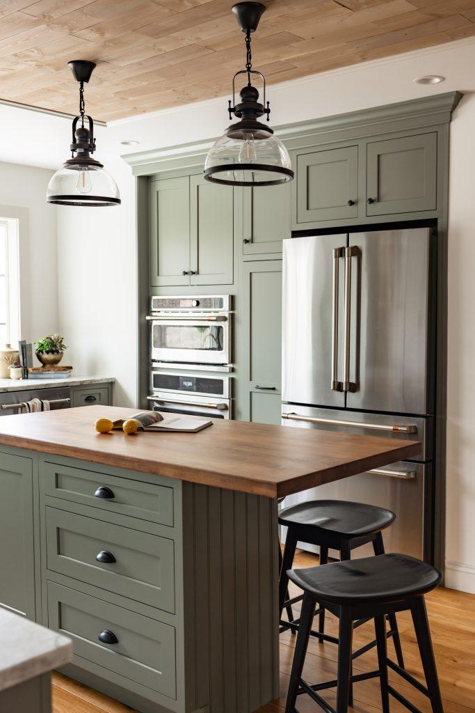 Full kitchen with green cabinetry, island, and coffered ceiling by Design House Interiors