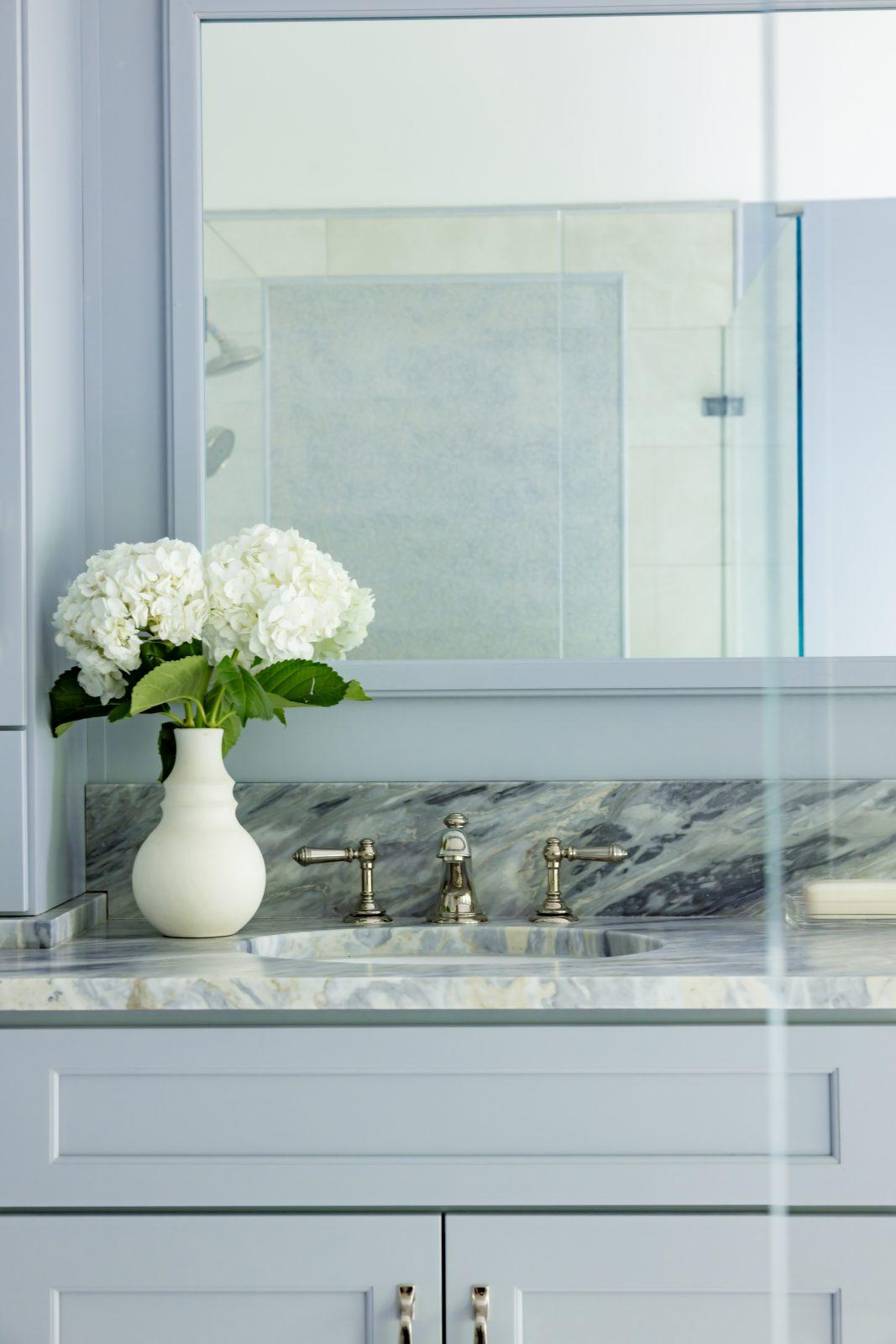 Blue gray bathroom vanity mirror with marble countertop and glass shower by Design House Interiors