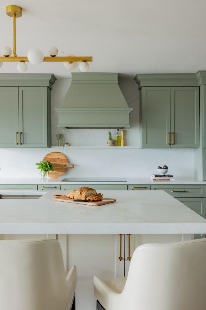 Sage green kitchen with brass hardware and open pantry with library ladder by Design House Interiors