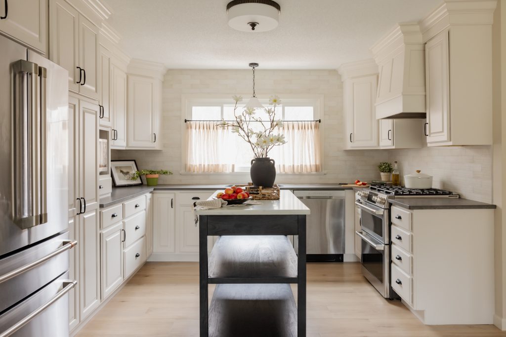 Cream kitchen cabinets with black hardware and built-in appliances by Design House Interiors